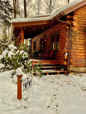 Een houten chalet met een overdekte veranda en een sneeuwbedekt dak.