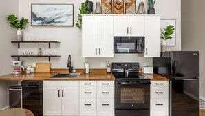 Une cuisine moderne avec des meubles blancs, un réfrigérateur noir, un four à micro-ondes et un lave-vaisselle.