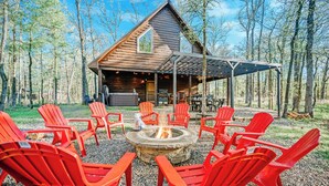 A cabin with a fire pit and red Adirondack chairs in a forest setting. - 2-Cabin Retreat| Pool Table | Hot Tubs | Mini Golf (Broken Bow)