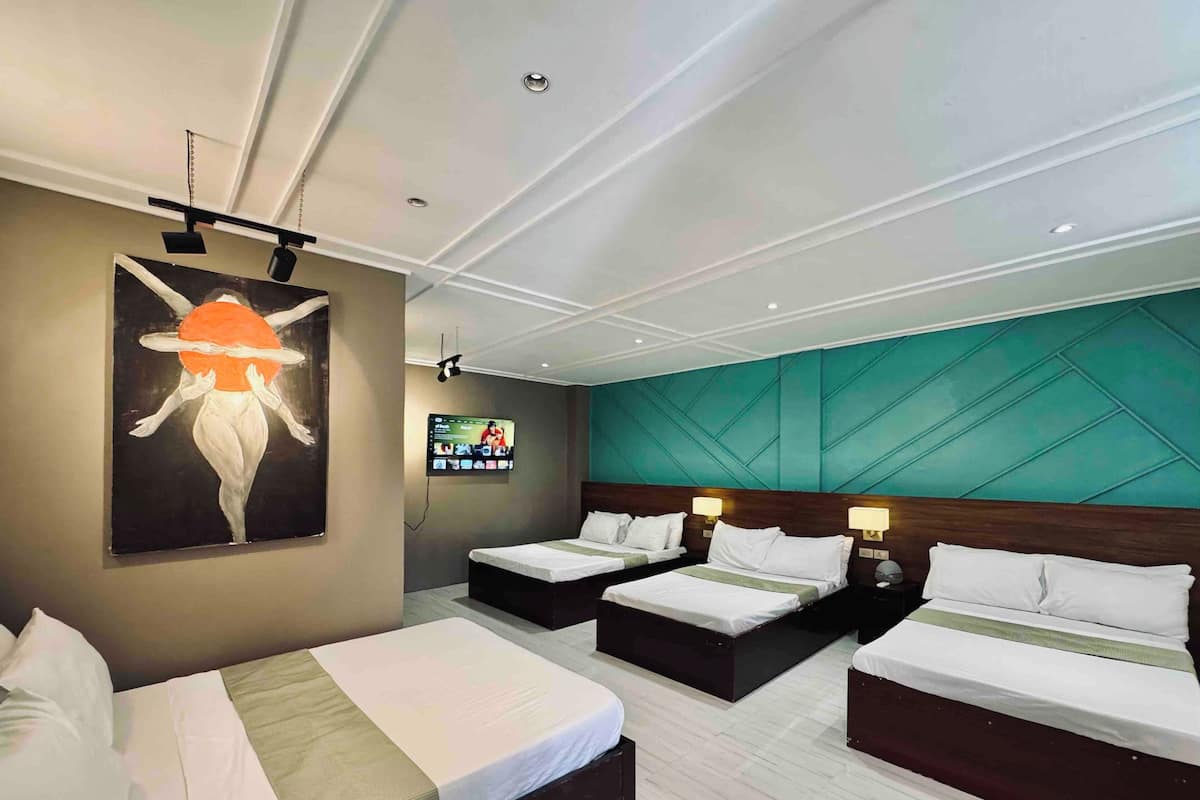 Hotelkamer met twee bedden, een groot schilderij aan de muur, een flatscreen televisie en een wand in turquoise.