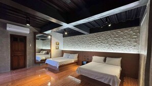 A hotel room with two beds, a wooden floor, a textured wall, and a ceiling with exposed beams.