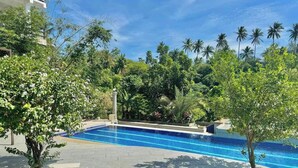A swimming pool surrounded by lush greenery and palm trees.
