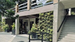 A modern building entrance with a covered outdoor area, a staircase, and a railing.