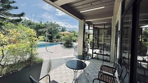 A covered outdoor area with a pool, two tables, and chairs.