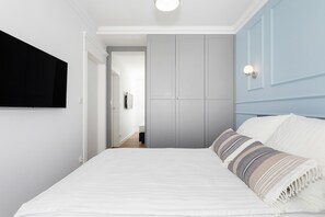 A bedroom with a bed, a TV mounted on the wall, and a wardrobe.