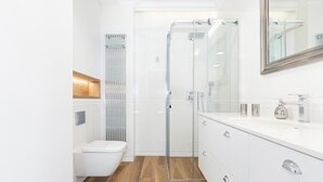 Ein modernes Badezimmer mit Duschkabine aus Glas, einer weißen Toilette und einem Waschtisch mit Spiegel.