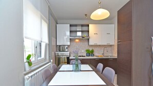 A modern kitchen with white cabinets, a built-in oven, and a dining area with a table and chairs. - House 2174/55597 (Istria - Rovinj), 600m from the beach (Rovinj)