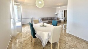A modern living room with a dining area, a grey sectional sofa, a blue armchair, and a hanging light fixture. - 3-room apartment, 2 bedrooms, sleeps 4 in Ajaccio (Ajaccio)