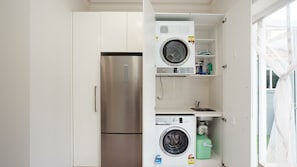 Eine kompakte Küche mit einem Edelstahlkühlschrank, einer Waschmaschine und einem Spülbecken.