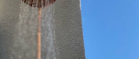 A close-up of a water spout with water flowing down a textured wall.