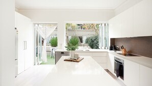Eine moderne Küche mit weißen Schränken, einer zentralen Kochinsel mit Pflanze und Blick auf den Garten.