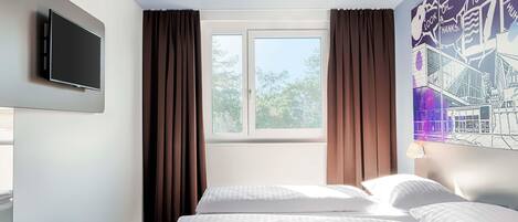 Habitación de hotel con dos camas, un televisor de pantalla plana montado en la pared, una ventana con cortinas y un mural con vista a la ciudad.