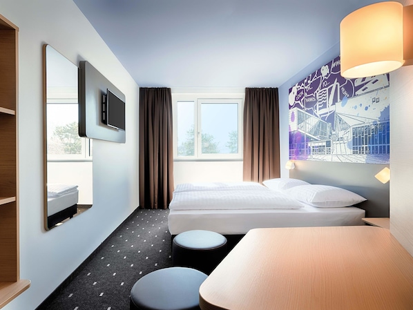 A hotel room with a bed, a TV, a desk, and a window with curtains. - B&B Hotel Wien-Stadthalle (Vienna)