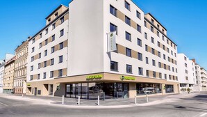Un hôtel moderne doté d’une réception, de plusieurs étages et offrant une vue sur un ciel dégagé.