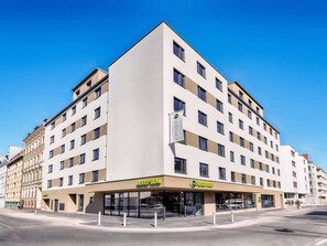 Un hôtel moderne doté d’une réception, de plusieurs étages et offrant une vue sur un ciel dégagé.