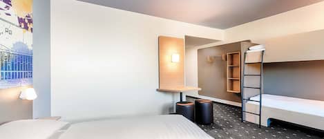Una camera d'albergo con un letto a castello, una scrivania con una sedia, uno scaffale a muro e un quadro.