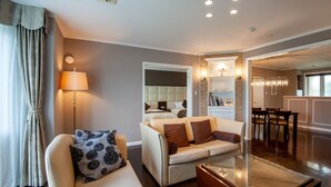 A modern living room with a sofa, a coffee table, and a lamp. There is a dining area with a table and chairs visible in the background. - camel hotel resort (Onjuku)