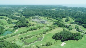 An aerial view of a golf course with multiple holes, water hazards, and a central clubhouse. - camel hotel resort (Onjuku)