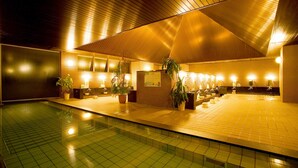 A modern indoor pool area with a tiled floor, wooden reception desk, and multiple sinks. - camel hotel resort (Onjuku)