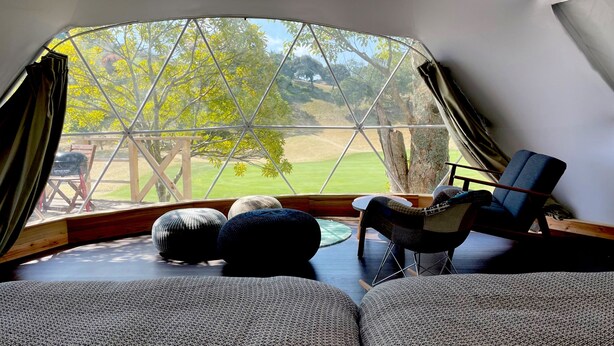 A cozy room with a curved ceiling, a view of a grassy field, and a dining area with a table and chairs. - camel hotel resort (Onjuku)