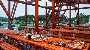 A wooden deck with picnic tables overlooking a body of water, surrounded by greenery. - camel hotel resort (Onjuku)