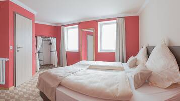 A hotel room with a large bed, a wardrobe, a mirror, and a window with curtains.