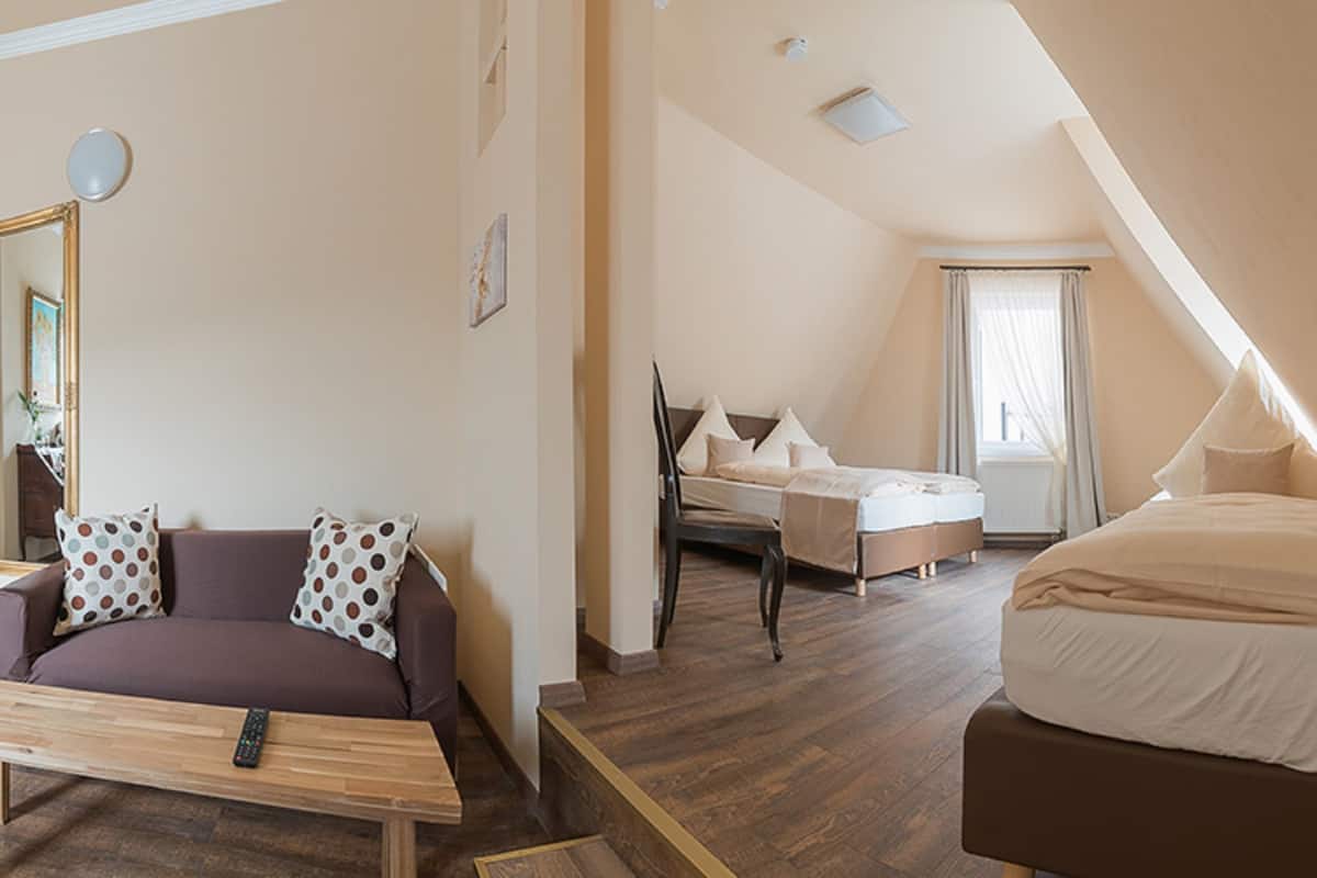 Moderni hotellihuone, jossa on puulattia, sohva, sänky ja työpöytä.