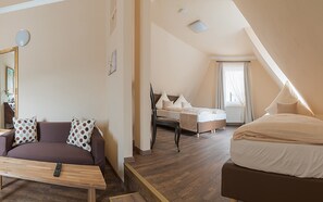 A modern hotel room with a wooden floor, a sofa, a bed, and a desk. - 7 Zwerge Übernachtungspension (Lohr am Main)