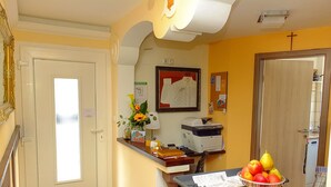 A reception area with a desk, a printer, a bulletin board, and a fruit bowl. - 7 Zwerge Übernachtungspension (Lohr am Main)