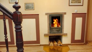 A room with a fireplace, wooden staircase, and framed pictures on the wall. - 7 Zwerge Übernachtungspension (Lohr am Main)