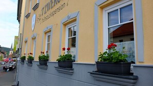 A building with the sign "Frühstückspension" indicating a breakfast room. There are potted plants on the windowsill. - 7 Zwerge Übernachtungspension (Lohr am Main)