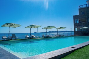 Una piscina al aire libre, sombrillas, tumbonas