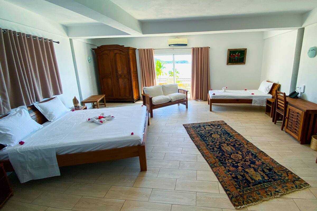 Ein Hotelzimmer mit zwei Betten, einer Schlafcouch, einem Holzschrank und einem großen Teppich.
