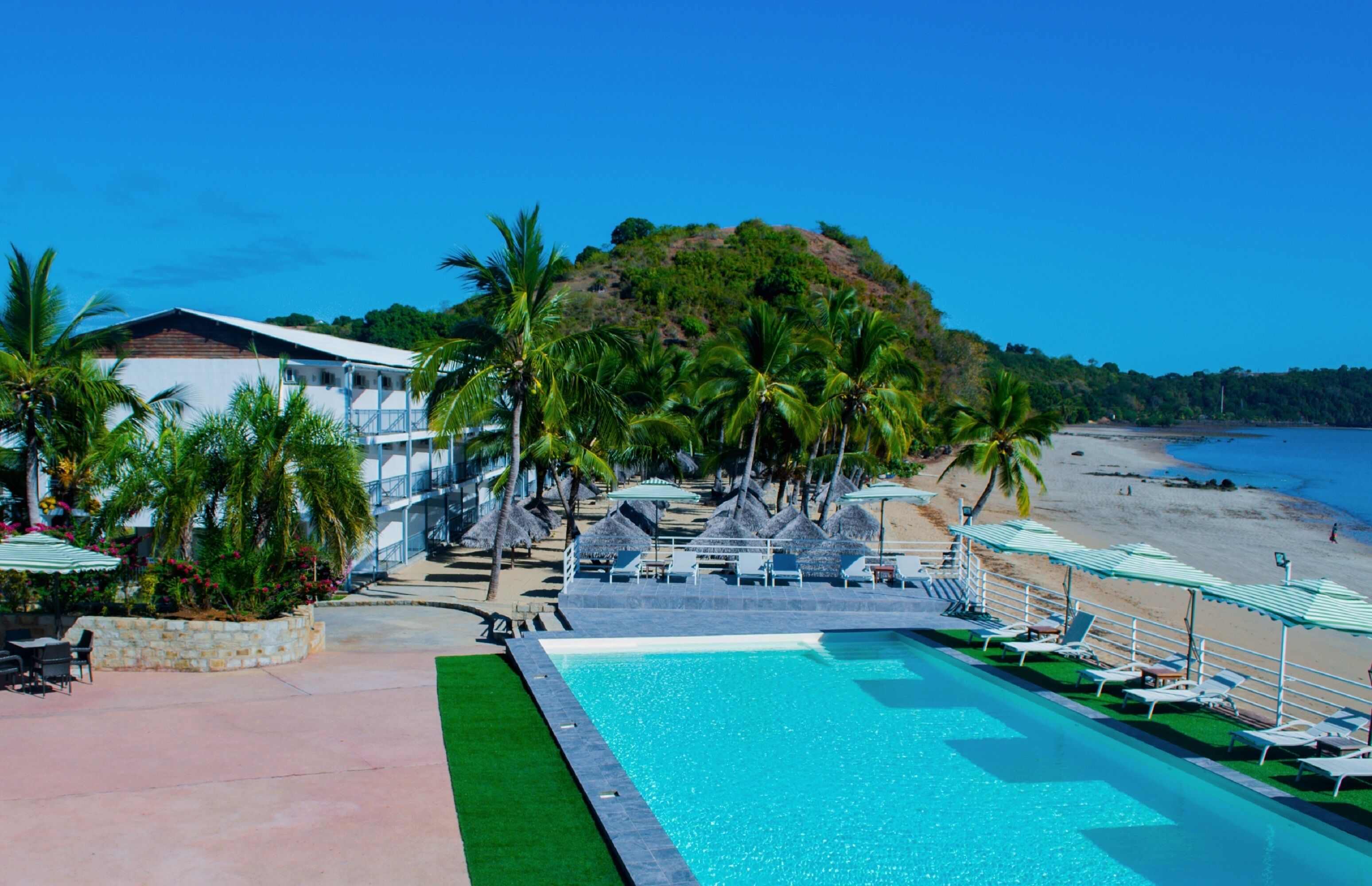 A pool area with lounge chairs, a swimming pool, and a beach view.