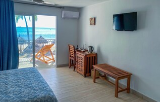 Una habitación con cama, un escritorio con sillas, un televisor y vista al océano.