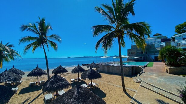 A beach with palm trees, lounge chairs, and umbrellas. - Orangea Beach Resort (Nosy Be)