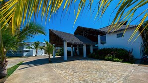 A white building with a thatched roof and a paved courtyard. - Orangea Beach Resort (Nosy Be)