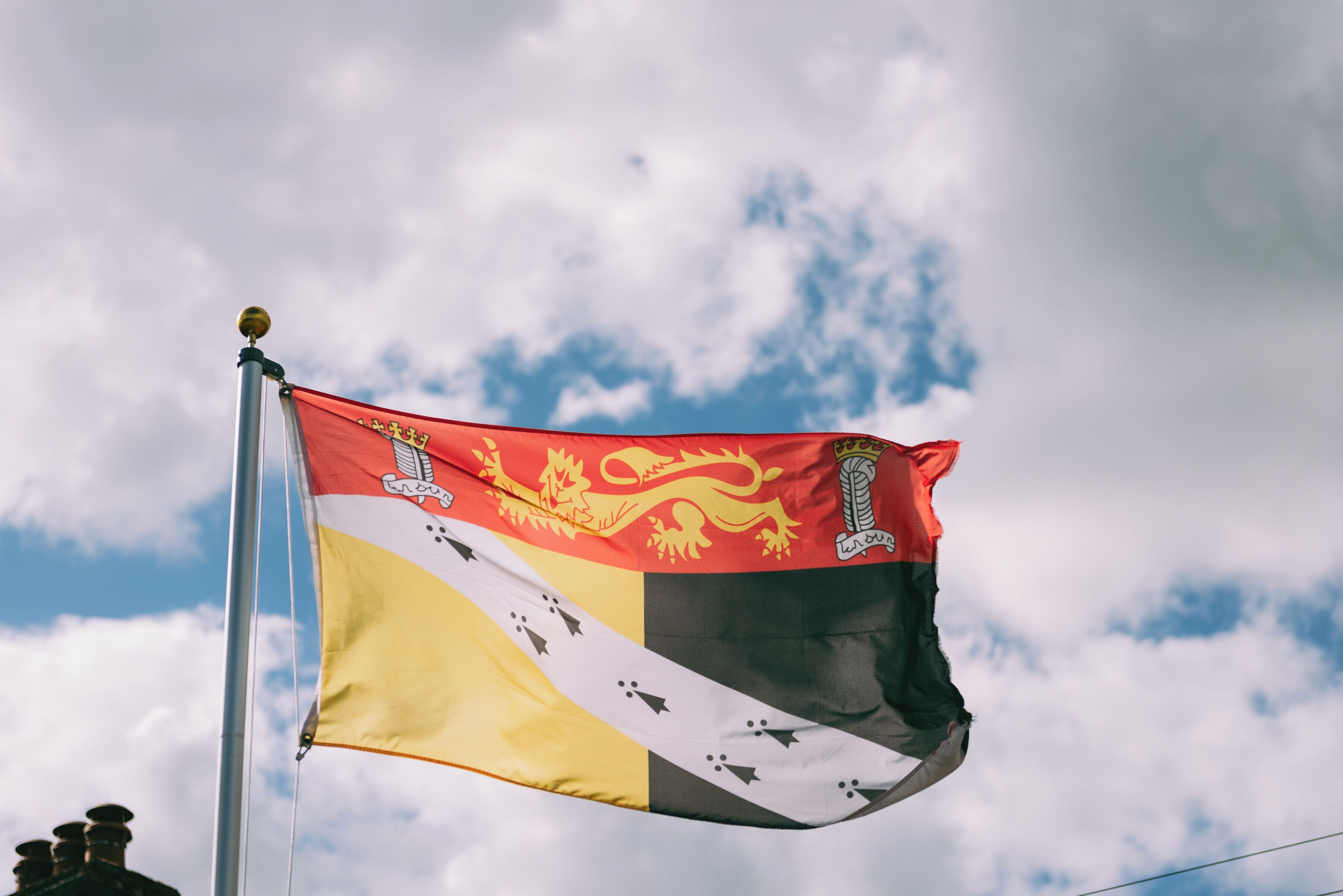 Una bandera en un asta contra un cielo parcialmente nublado.