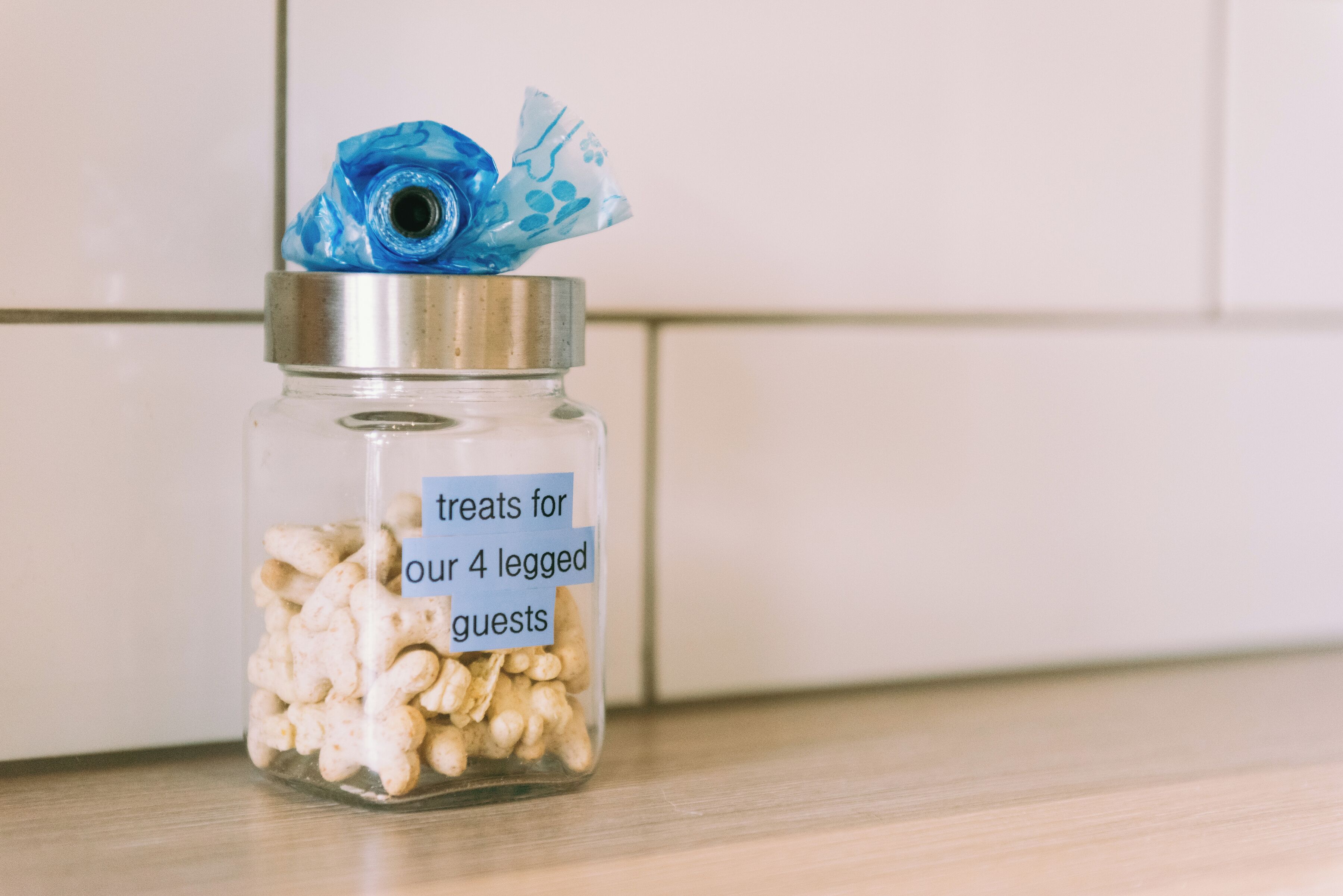 A glass jar with a metal lid containing treats for guests, placed on a wooden surface.