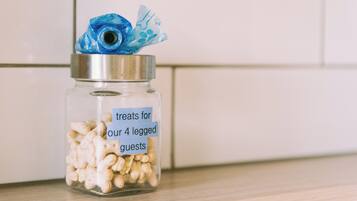 A glass jar with a metal lid containing treats for guests, placed on a wooden surface.