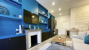 Ein modernes Wohnzimmer mit blauer Akzentwand, einem Kamin, einer Couch und einem Essbereich.