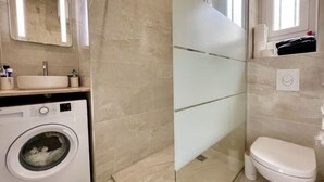 Ein Badezimmer mit Waschmaschine, Waschbecken, Toilette und Duschbereich.