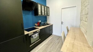 Eine kleine Küche mit schwarzen Schränken, einer Holzarbeitsplatte und einer blauen Wand.