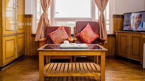A room with wooden furniture, a television, and a window with curtains. - Doma Residency (Gangtok)