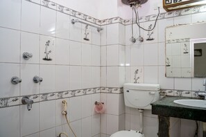 A bathroom with white tiled walls, a toilet, a sink, and a shower area. - Doma Residency (Gangtok)