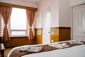 A hotel room with a bed, a desk, and a window with curtains. - Doma Residency (Gangtok)