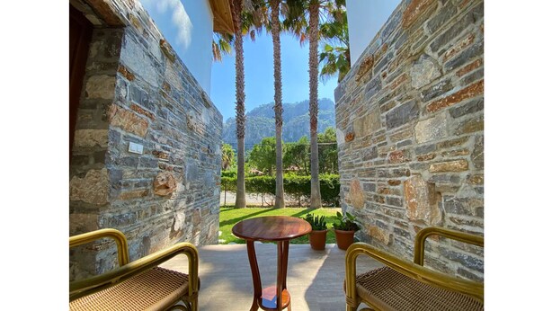 A stone-walled outdoor seating area with two wicker chairs and a small round table. - Villa Merry - Dalyan Stonehouse with Palmtrees (Muğla)