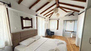 A bedroom with a large bed, wooden beams on the ceiling, a chair, and a small table. - Villa Merry - Dalyan Stonehouse with Palmtrees (Muğla)