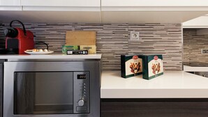 Een moderne keuken met een magnetron, een rode waterkoker en twee dozen chocolade op het aanrecht.
