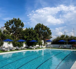 A swimming pool with lounge chairs and umbrellas, surrounded by greenery and a clear sky. - Smart Accomodation Rhodes by GHH (Rhodes)